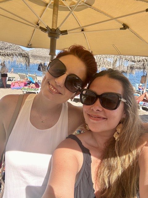 Two members under a parasol on the beach